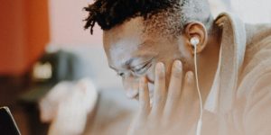 Man working with headphones one smiling at laptop