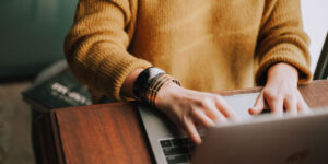 woman typing on computer in yellow sweater