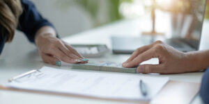 Businessman giving of money, cash dollars to his partner over an office desk - loan, payment and